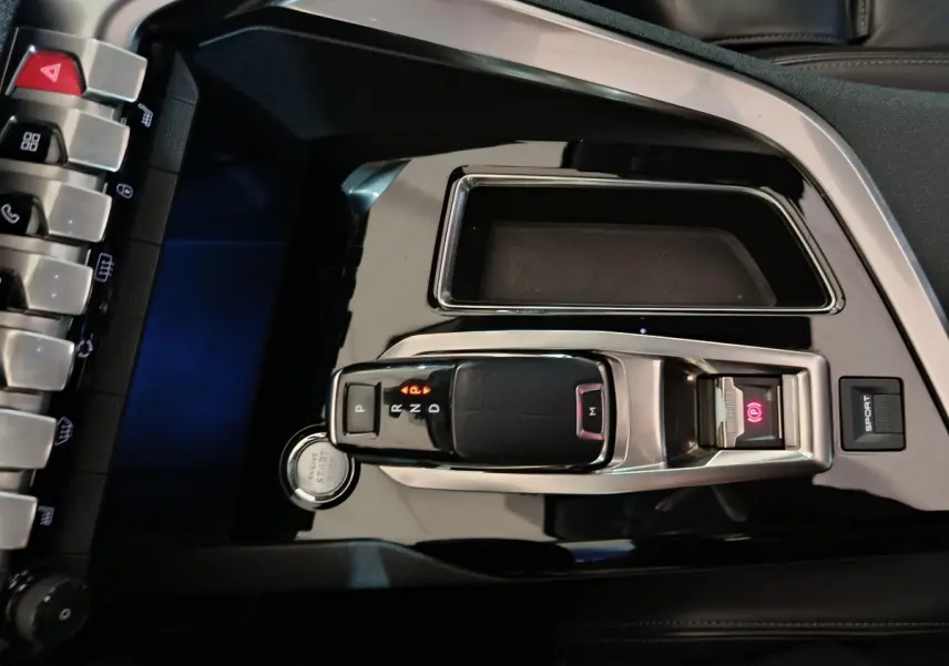 Vue plongeante sur la console centrale noire brillante du Peugeot 3008 blanc, avec levier de vitesse automatique et bouton start.