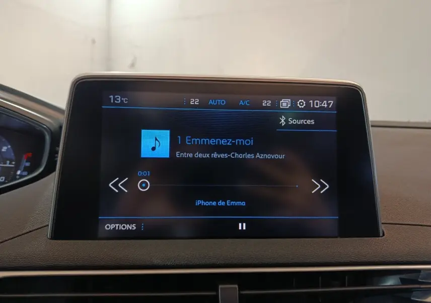 Écran tactile central du tableau de bord du Peugeot 3008 blanc, affichant une musique en cours de lecture.