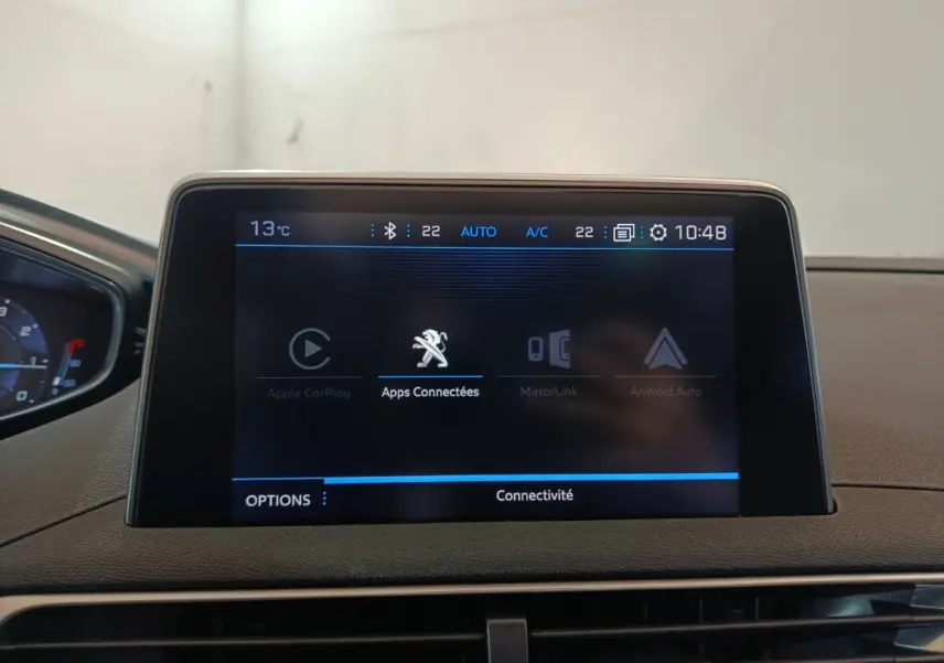 Écran tactile central affichant les applications connectées dans l'habitacle du Peugeot 3008 blanc, vue de face.