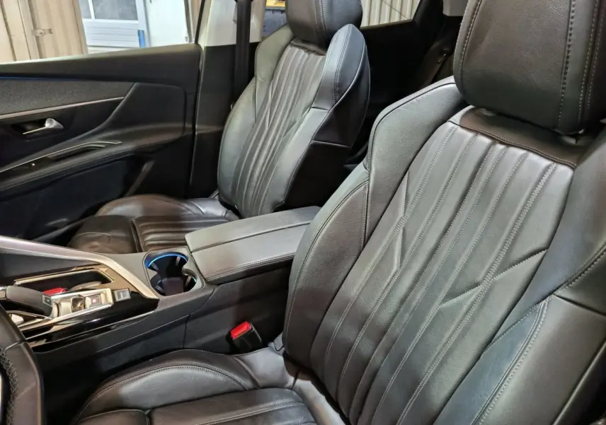 Intérieur du Peugeot 3008 Puretech 130, vue rapprochée des sièges avant en cuir noir et console centrale.