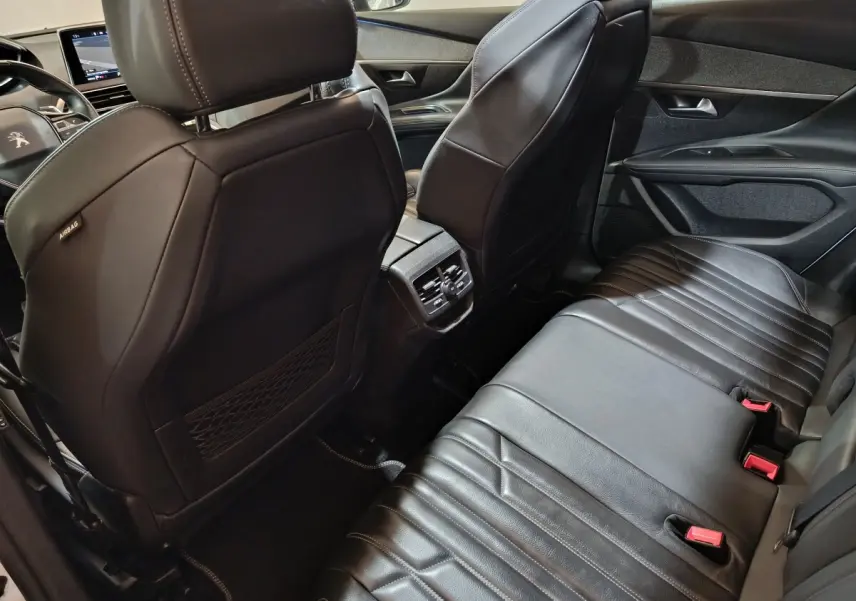 Vue intérieure arrière du Peugeot 3008 blanc, sièges en cuir noir et console centrale avec aérateurs arrière.