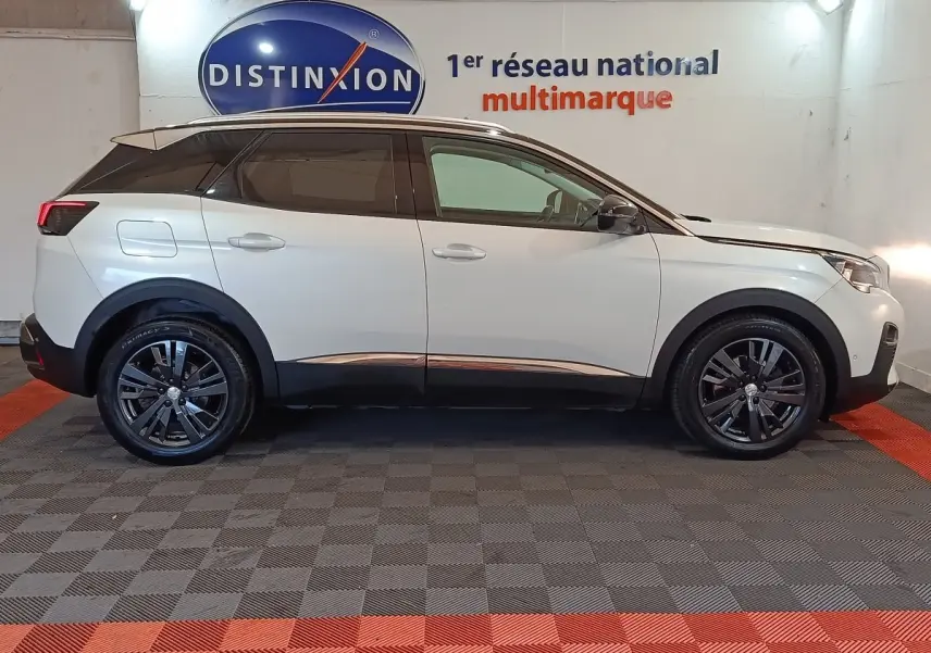 Profil droit d’un Peugeot 3008 blanc 2019 Puretech Allure avec jantes noires et toit noir dans un showroom.