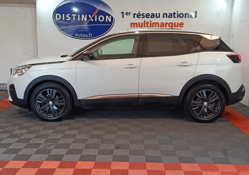 Profil droit du Peugeot 3008 blanc de 2019, avec jantes noires et toit noir contrastant, en intérieur showroom.