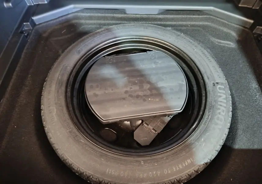 Gros plan sur la roue de secours dans le coffre d'un Peugeot 3008 blanc, avec rangement d'outils visible.