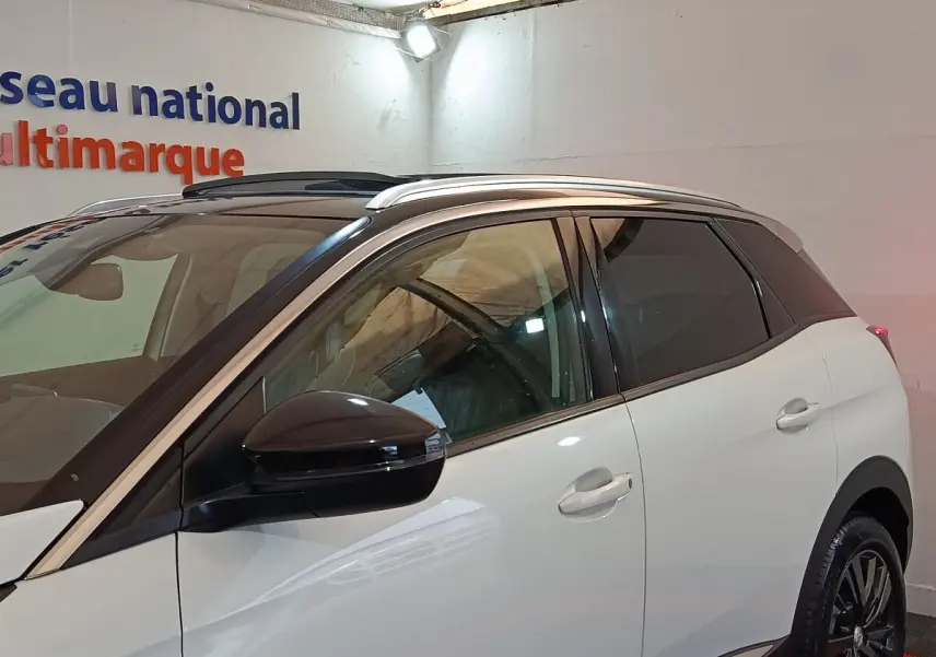 Vue latérale droite d’un Peugeot 3008 blanc avec rétroviseur noir et toit panoramique en intérieur showroom.