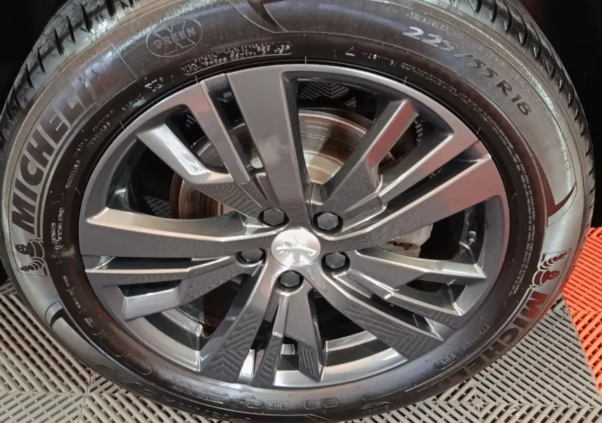 Gros plan sur la jante alliage gris foncé et pneu Michelin d’un Peugeot 3008 blanc, vue latérale droite.