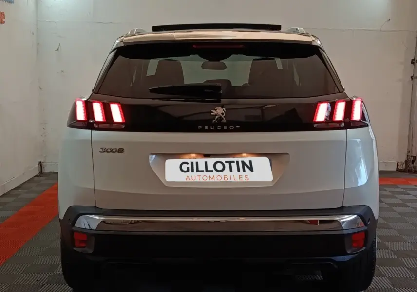 Vue arrière d’un Peugeot 3008 blanc avec feux LED allumés et toit noir dans un garage.