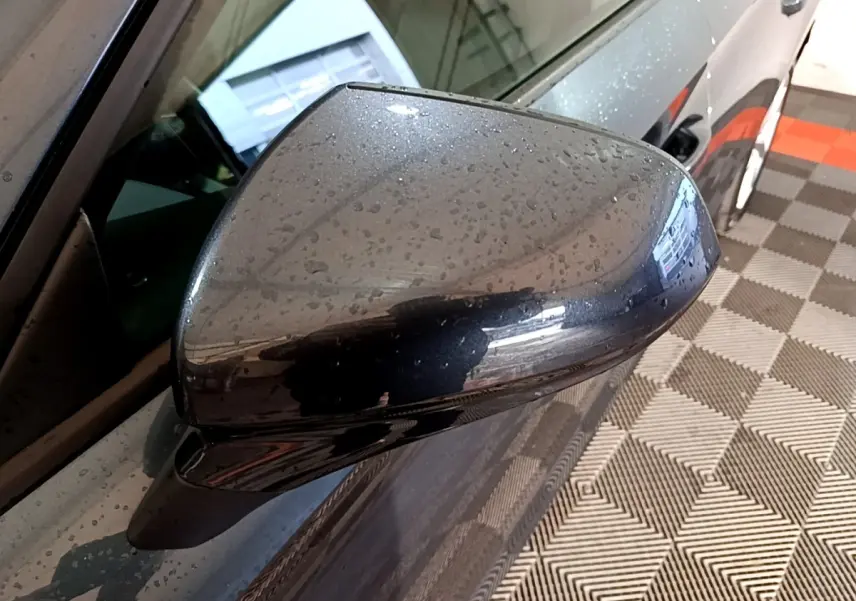 Rétroviseur droit gris clair de la SEAT LEON 2023 avec gouttes d'eau, vue rapprochée côté conducteur.