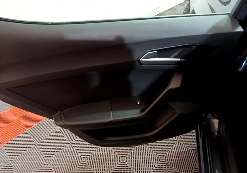 Vue intérieure sur la porte avant droite noire du SEAT Leon 2023, avec poignée argentée et commande de vitre électrique.