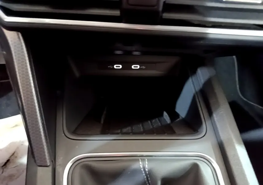 Gros plan sur la console centrale du SEAT Leon 2023, montrant la zone de recharge par induction et ports USB.