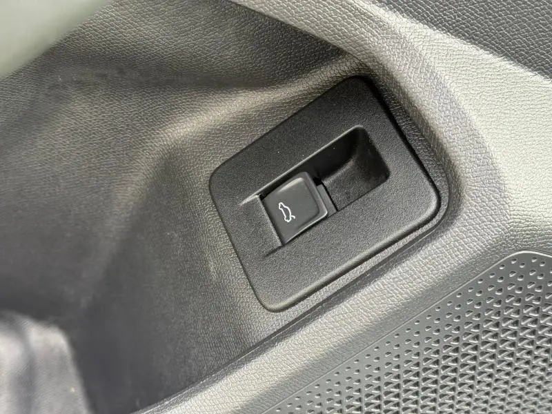 Bouton d'ouverture de coffre en plastique noir sur panneau intérieur d'une CUPRA Formentor 2.0 TDI 2025.