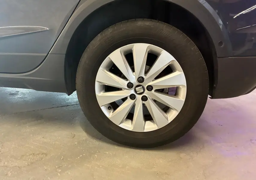 Gros plan sur la roue arrière droite d’un SEAT Arona gris foncé, mettant en valeur la jante alliage au design moderne.