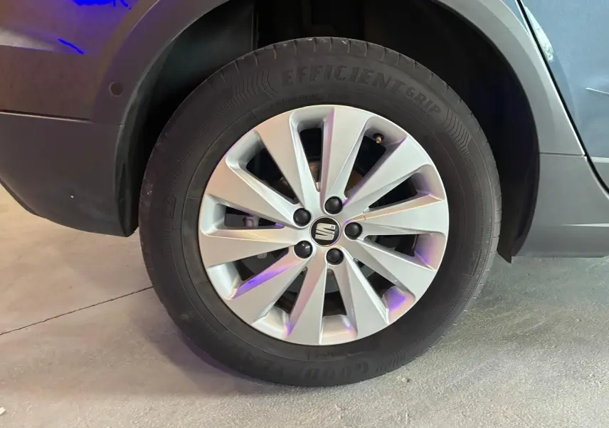 Gros plan sur la roue avant gauche d'un SEAT Arona gris foncé, avec jante alliage à dix branches et logo central.