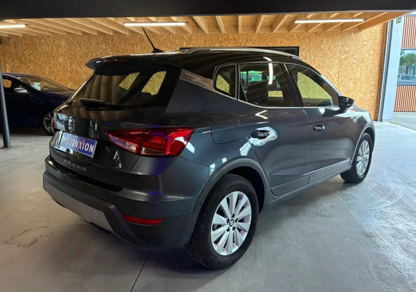 SEAT Arona gris foncé vu en 3/4 arrière droit, avec toit noir et jantes argentées dans un garage.