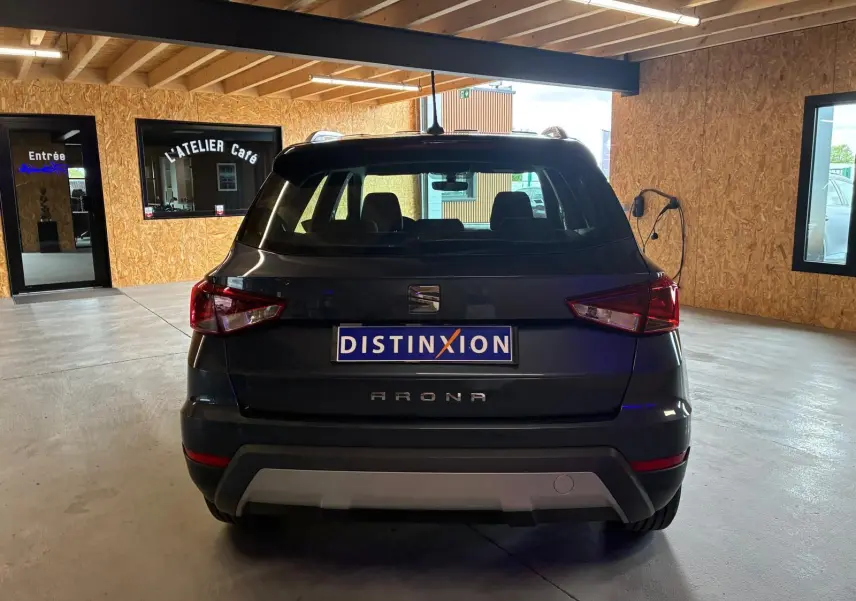 Vue arrière d'un SEAT Arona gris foncé stationné en intérieur avec plaques Distinxion visibles.