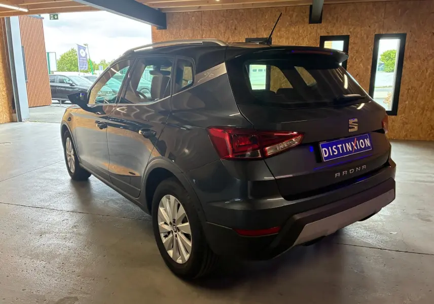 SEAT Arona gris foncé vue 3/4 arrière droit, avec jantes alliage et toit noir contrasté dans un garage.