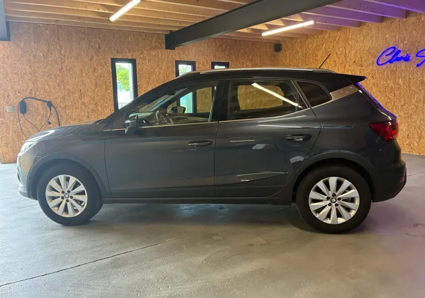 SEAT Arona gris foncé vue de profil côté gauche, avec jantes alliage et toit noir dans un garage.