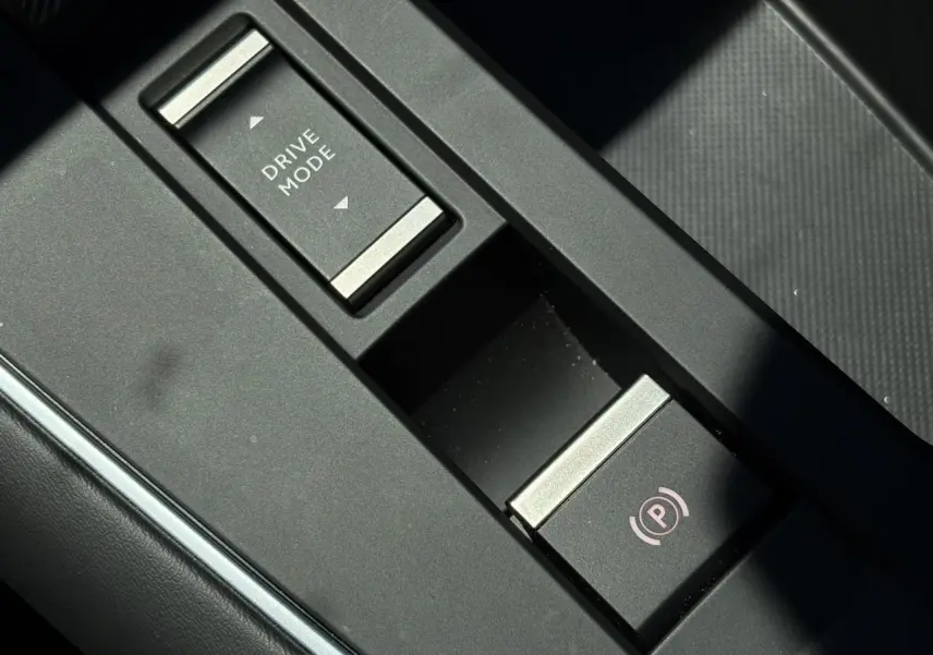 Gros plan sur la console centrale noire du Citroën C5 Aircross Hybrid avec bouton Drive Mode et frein à main électrique.