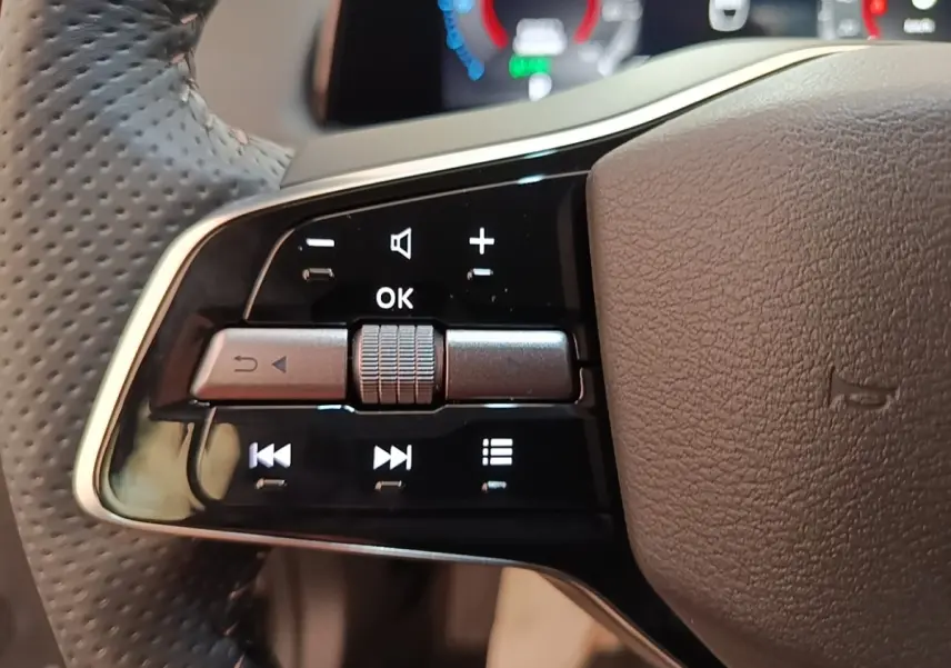 Gros plan sur les commandes gauche du volant cuir noir perforé du Nissan Ariya 63kWh 218ch Engage 2026.