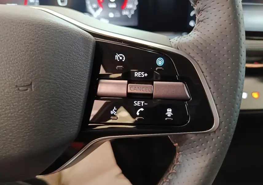 Gros plan sur la partie droite du volant cuir noir du Nissan Ariya 63kWh avec commandes multifonctions éclairées.