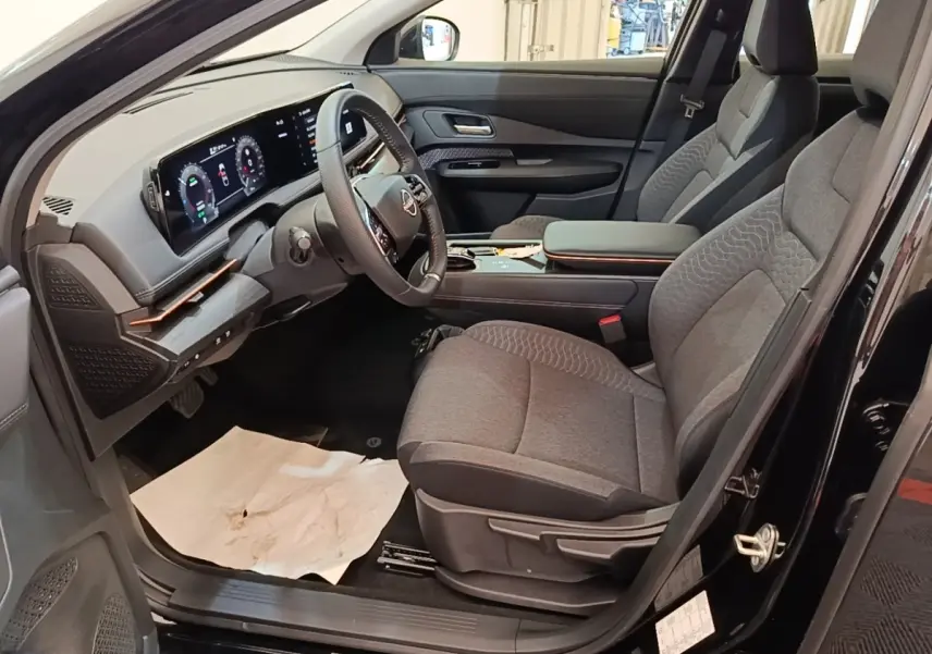 Vue intérieure côté conducteur du Nissan Ariya noir 2026, montrant sièges gris et tableau de bord numérique large.