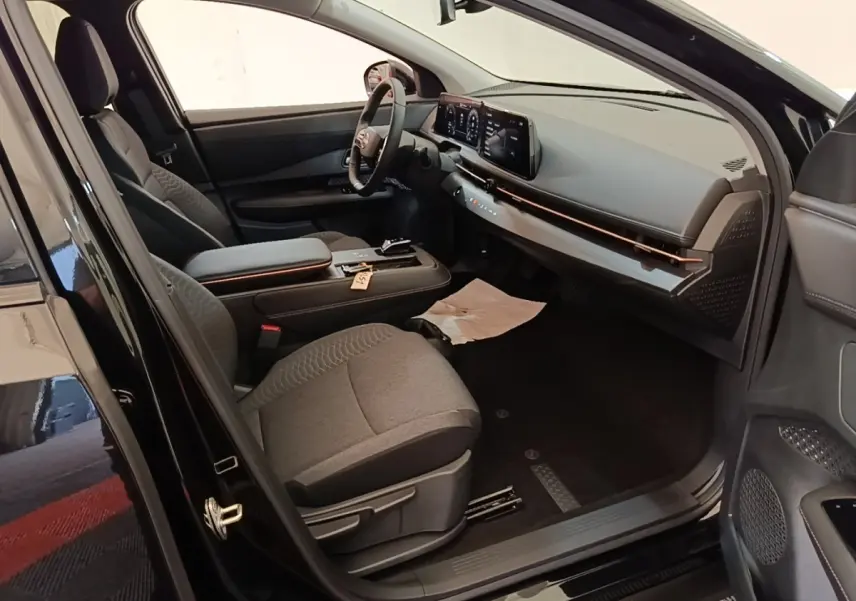 Intérieur avant droit du Nissan Ariya noir 2026, avec tableau de bord moderne et sièges tissu gris.