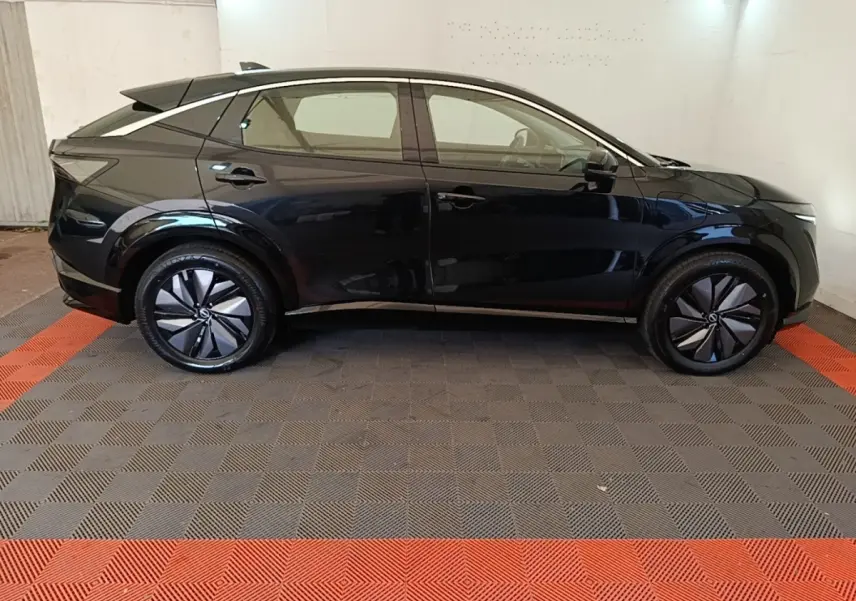 Vue de profil côté gauche du Nissan Ariya noir 63kWh 218ch Engage avec jantes stylisées et toit incliné.