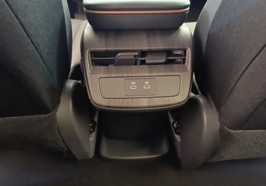 Vue rapprochée de la console arrière noire du Nissan Ariya 63kWh avec prises USB-C et aérateurs.