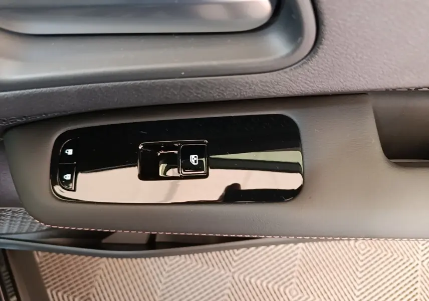Détail de la commande de lève-vitre électrique sur la porte côté conducteur du Nissan Ariya noir 2026.