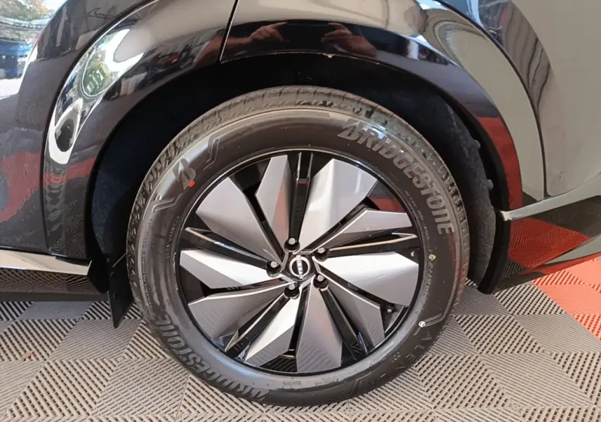 Gros plan sur la roue arrière droite noire du Nissan Ariya 63kWh 218ch Engage avec jante design bicolore.