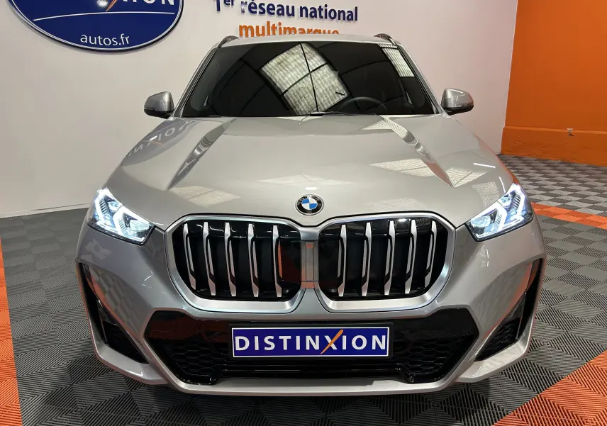 Vue frontale d'un BMW X1 sDrive20d M Sport 2024 en couleur Spacesilber avec phares LED allumés et calandre imposante.