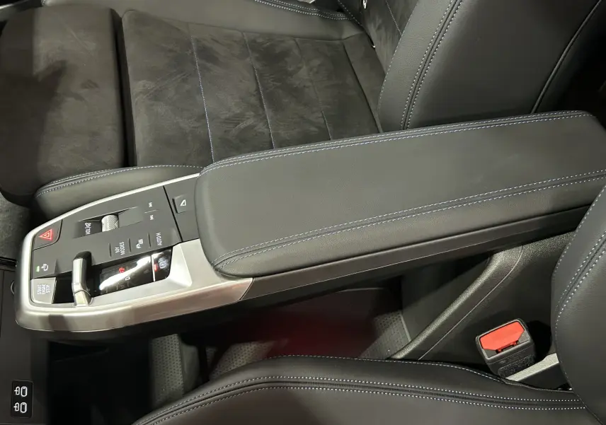 Gros plan sur la console centrale et siège avant en cuir noir avec surpiqûres bleues du BMW X1 2024 Spacesilber.