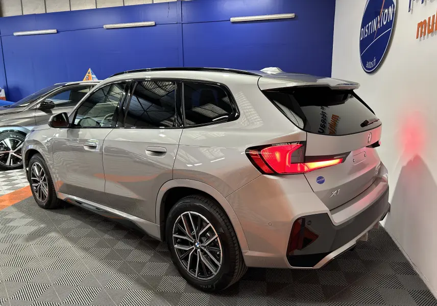 BMW X1 sDrive20d M Sport 2024 en Spacesilber, vue 3/4 arrière droit avec feux LED allumés et jantes sport.