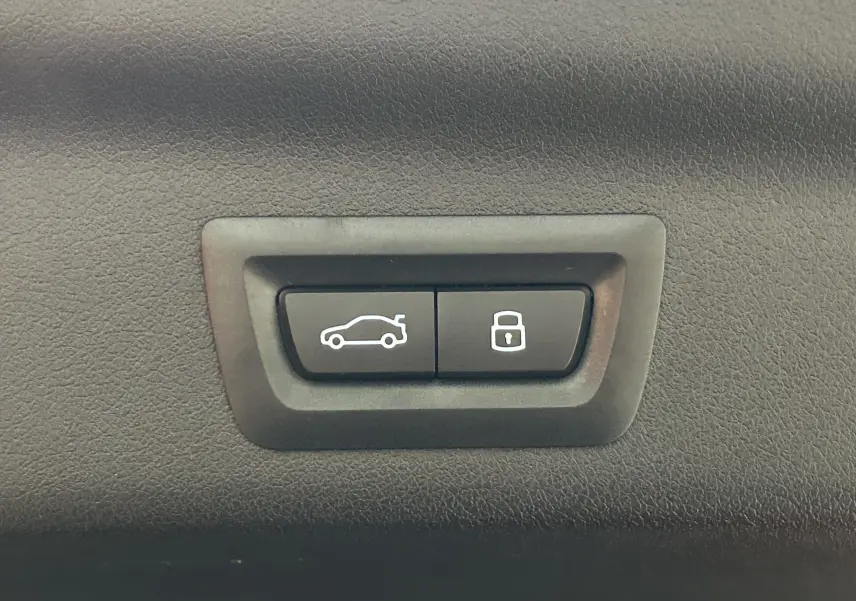 Boutons de commande pour ouverture du hayon et verrouillage, intégrés dans l'intérieur noir du BMW X1 Spacesilber 2024.