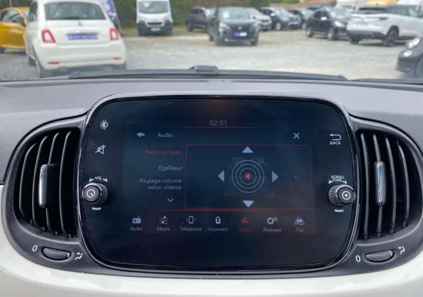 Écran tactile central de la Fiat 500 blanche 2024 montrant les réglages audio avec aérateurs latéraux noirs.
