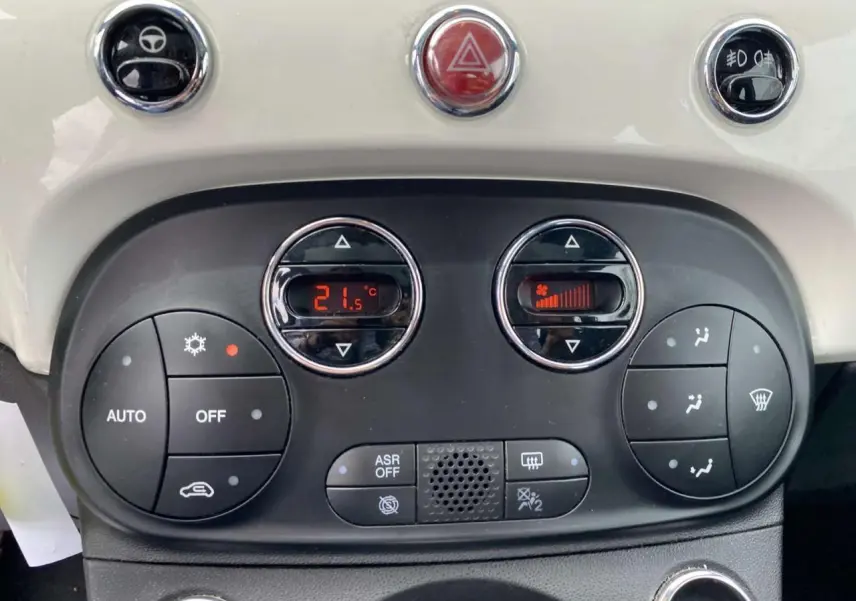 Tableau de bord de Fiat 500 2024 blanc, vue rapprochée des commandes de climatisation automatique et boutons fonctionnels.