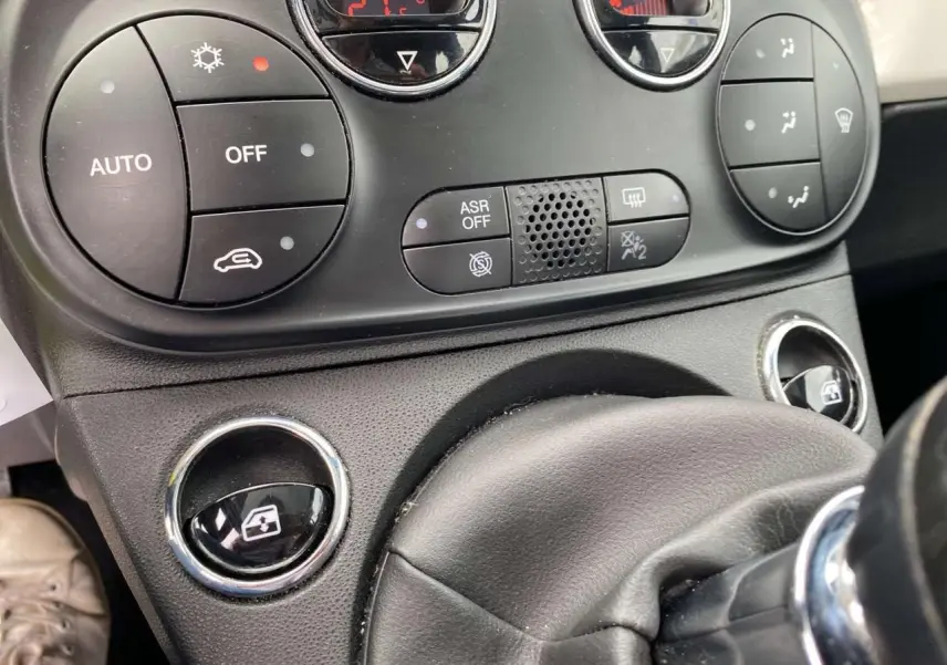 Gros plan sur la console centrale et commandes de climatisation de la Fiat 500 blanche 2024, avec boutons ronds noirs.