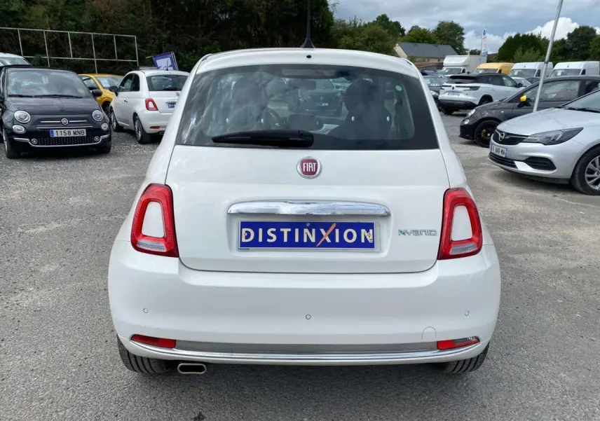 Vue arrière d'une Fiat 500 blanche 2024 avec badge Hybrid et radar de recul sur un parking extérieur.