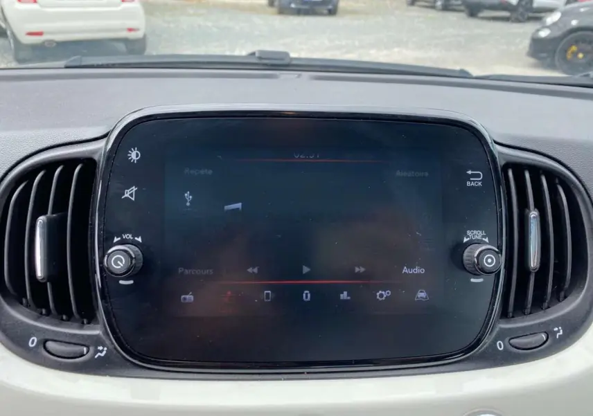 Écran tactile central du tableau de bord de la Fiat 500 blanche 2024 avec commandes audio et ventilation visibles.