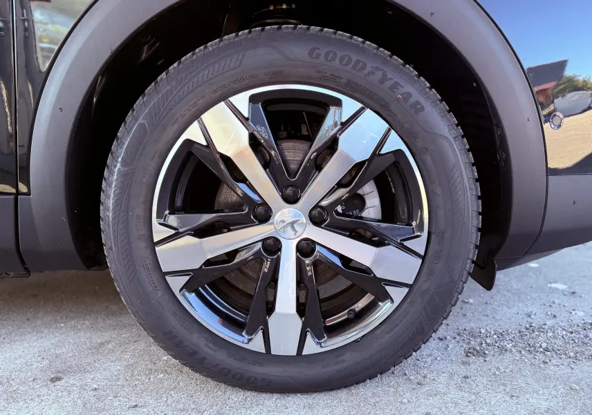 Gros plan sur la roue avant gauche noire perle métal du Peugeot 3008 1.2 PureTech 130ch GT avec jante alliage bicolore.