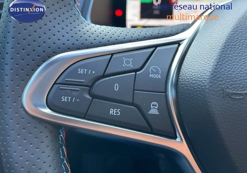 Gros plan sur les commandes au volant en cuir perforé bleu et noir du Renault Captur E-Tech hybride 2025.