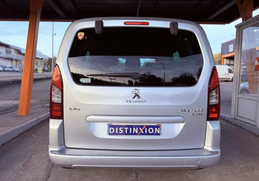 Vue arrière d'un Peugeot Partner Tepee gris 2014 avec logo et plaques distinctives sous un abri.