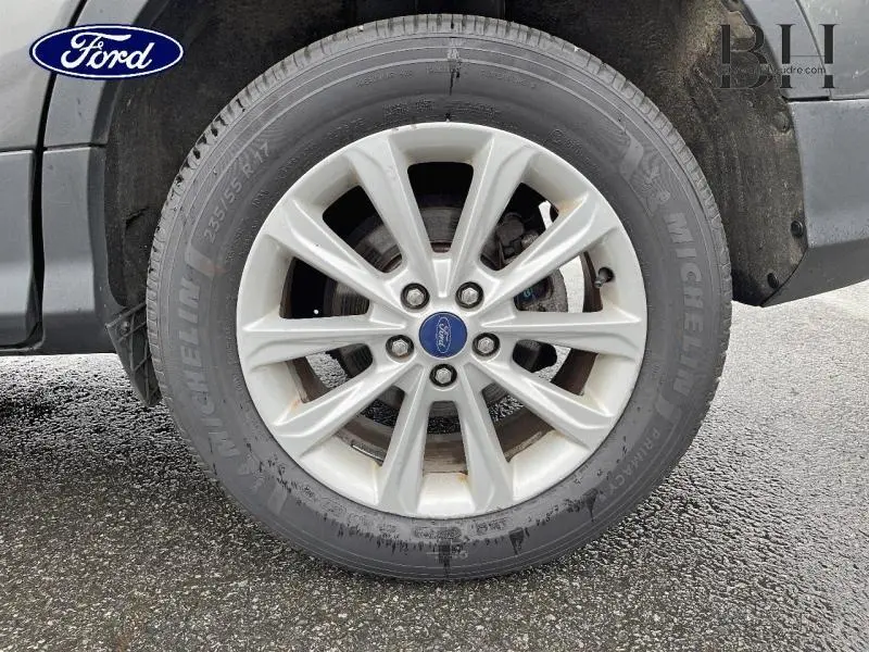 Gros plan sur la roue avant gauche du Ford Kuga gris Magnetic avec jante alu et pneu Michelin humide.