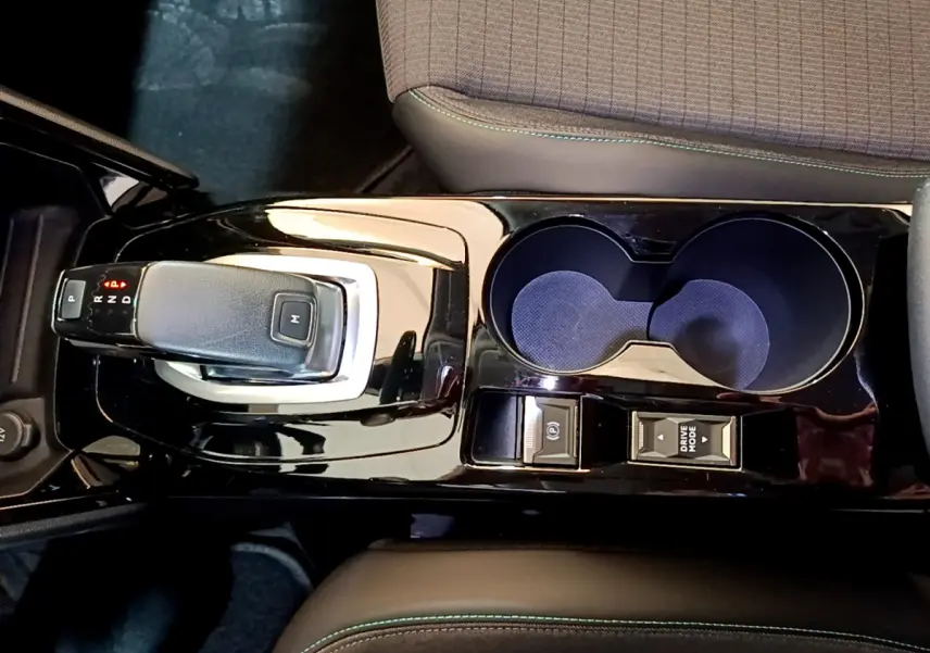 Vue plongeante sur la console centrale noire brillante du Peugeot 2008 gris clair, avec levier de vitesse automatique et porte-gobelets.