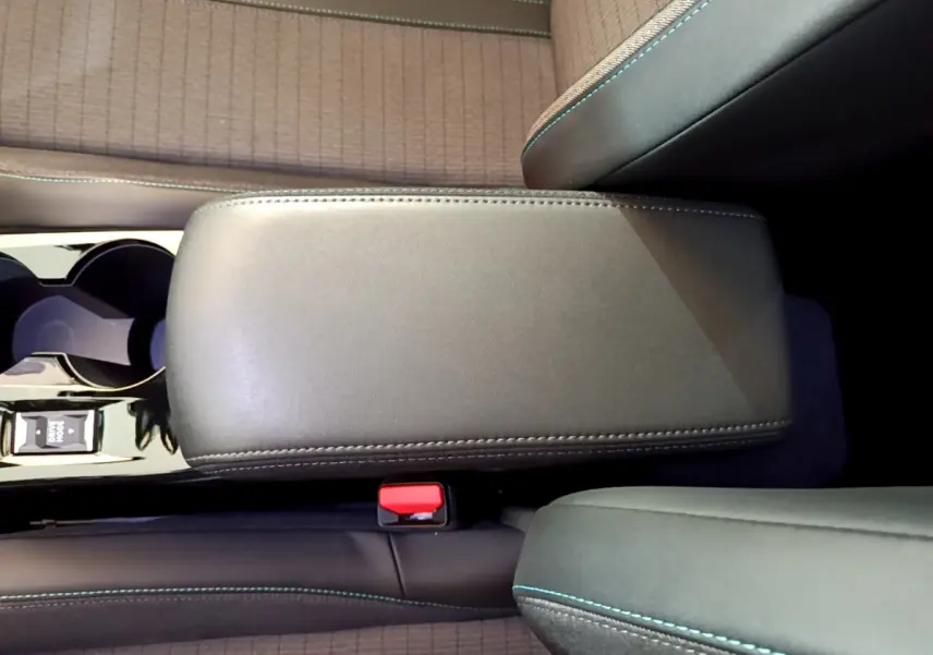 Vue plongeante sur l'accoudoir central en cuir noir et la console avec porte-gobelets du Peugeot 2008 gris clair.