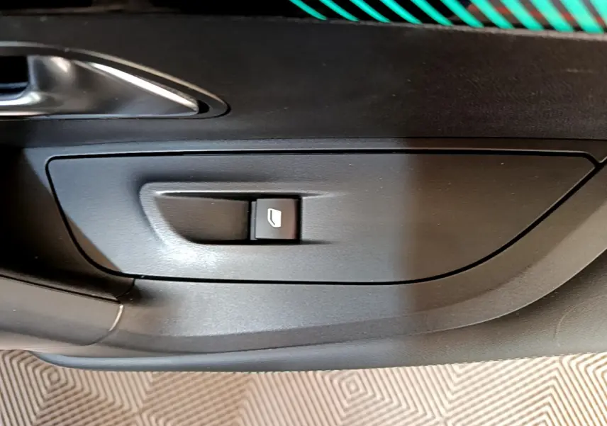 Bouton de commande de lève-vitre sur la porte intérieure côté gauche d’un Peugeot 2008 gris clair.