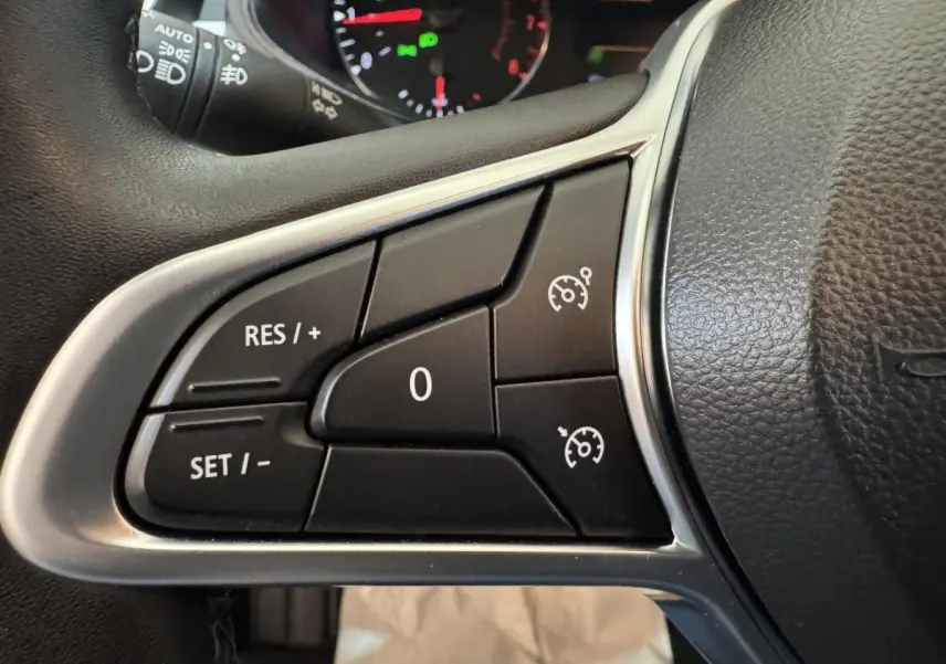 Gros plan sur les commandes de régulateur de vitesse au volant cuir noir de la Renault Clio Business TCe 100 GPL 2023.