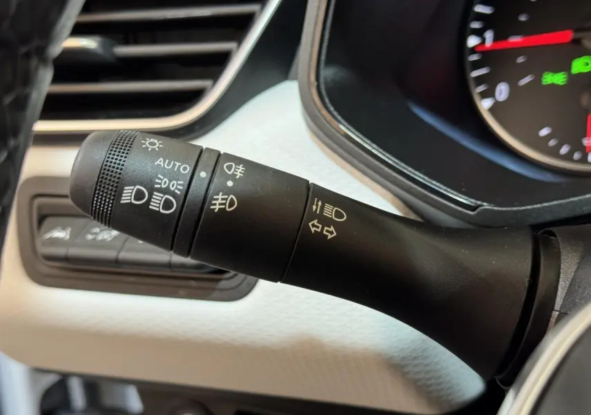 Gros plan sur la commande des phares et clignotants dans l’habitacle blanc d’une Renault Clio Business TCe 100 GPL 2023.