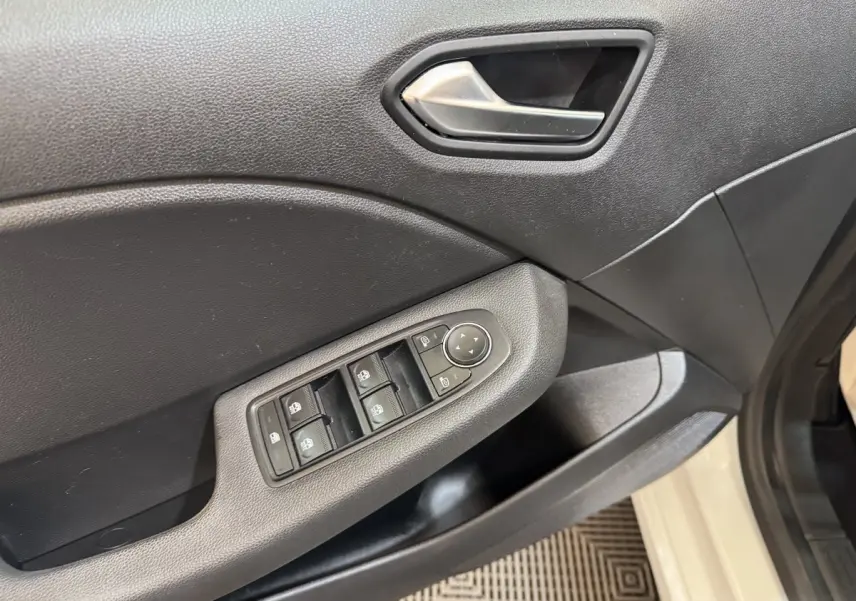 Gros plan sur la porte avant gauche de la Renault Clio Business blanche, montrant les commandes des vitres et rétroviseurs.