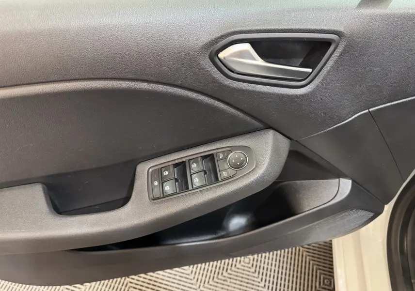 Gros plan sur la porte avant gauche noire de la Renault Clio blanche 2023 avec commandes électriques des vitres.
